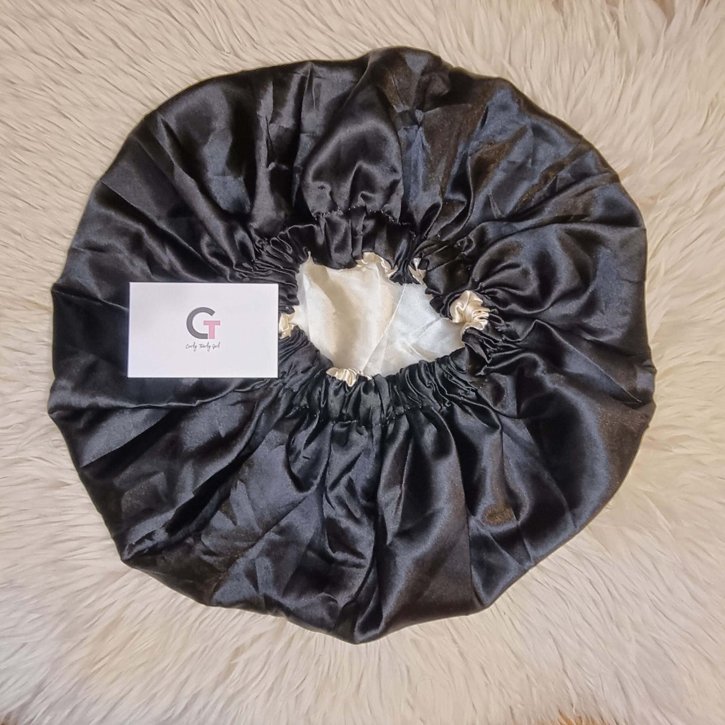 Black and gold reversible satin bonnet on cream rug