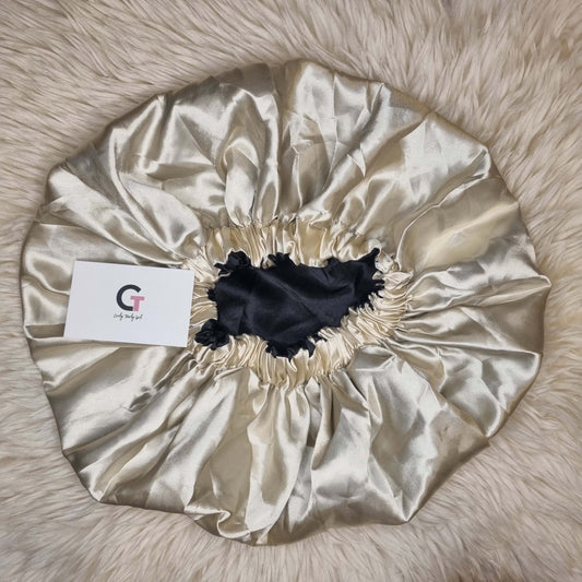 Gold and black reversible satin bonnet on cream rug