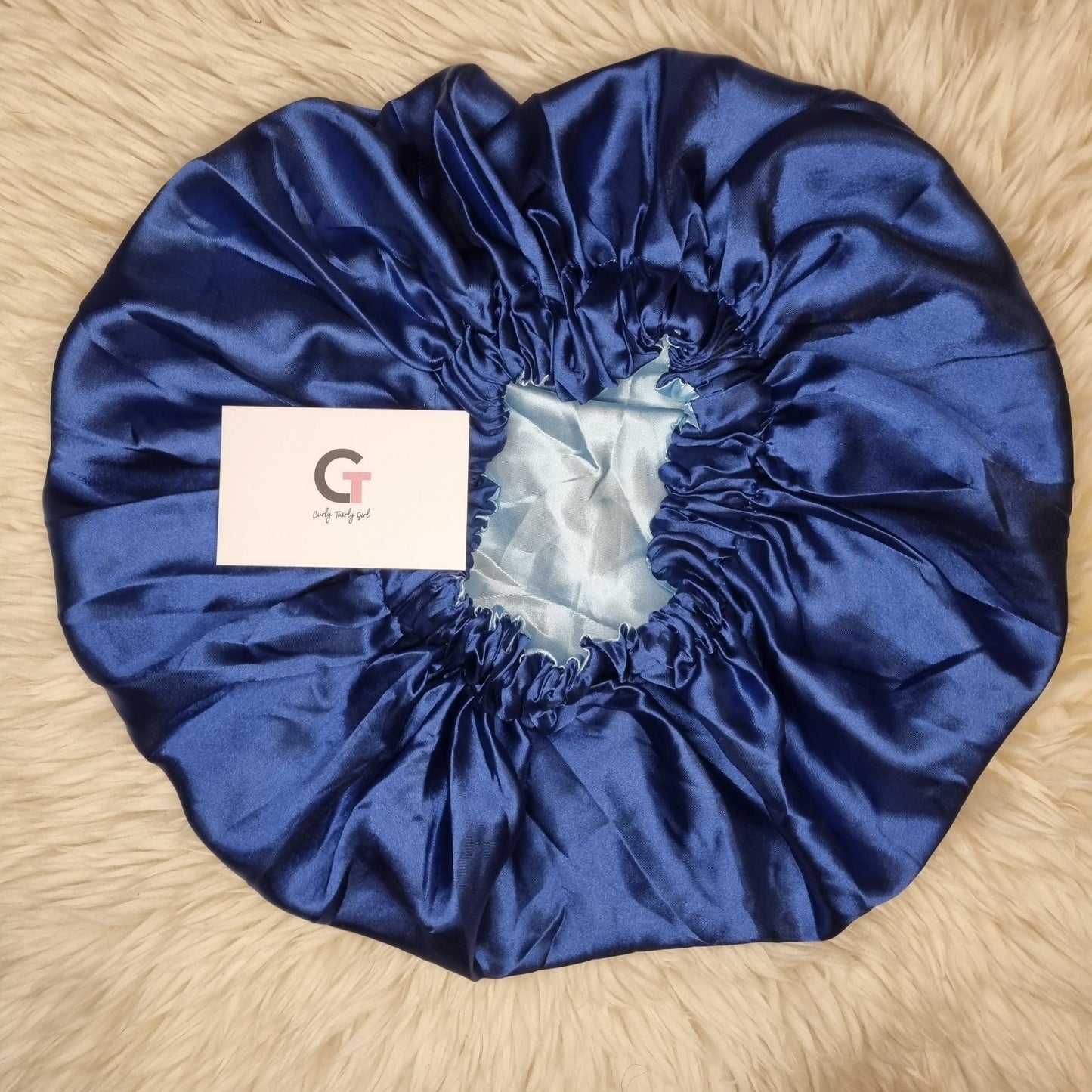 Royal blue reversible satin bonnet on cream rug
