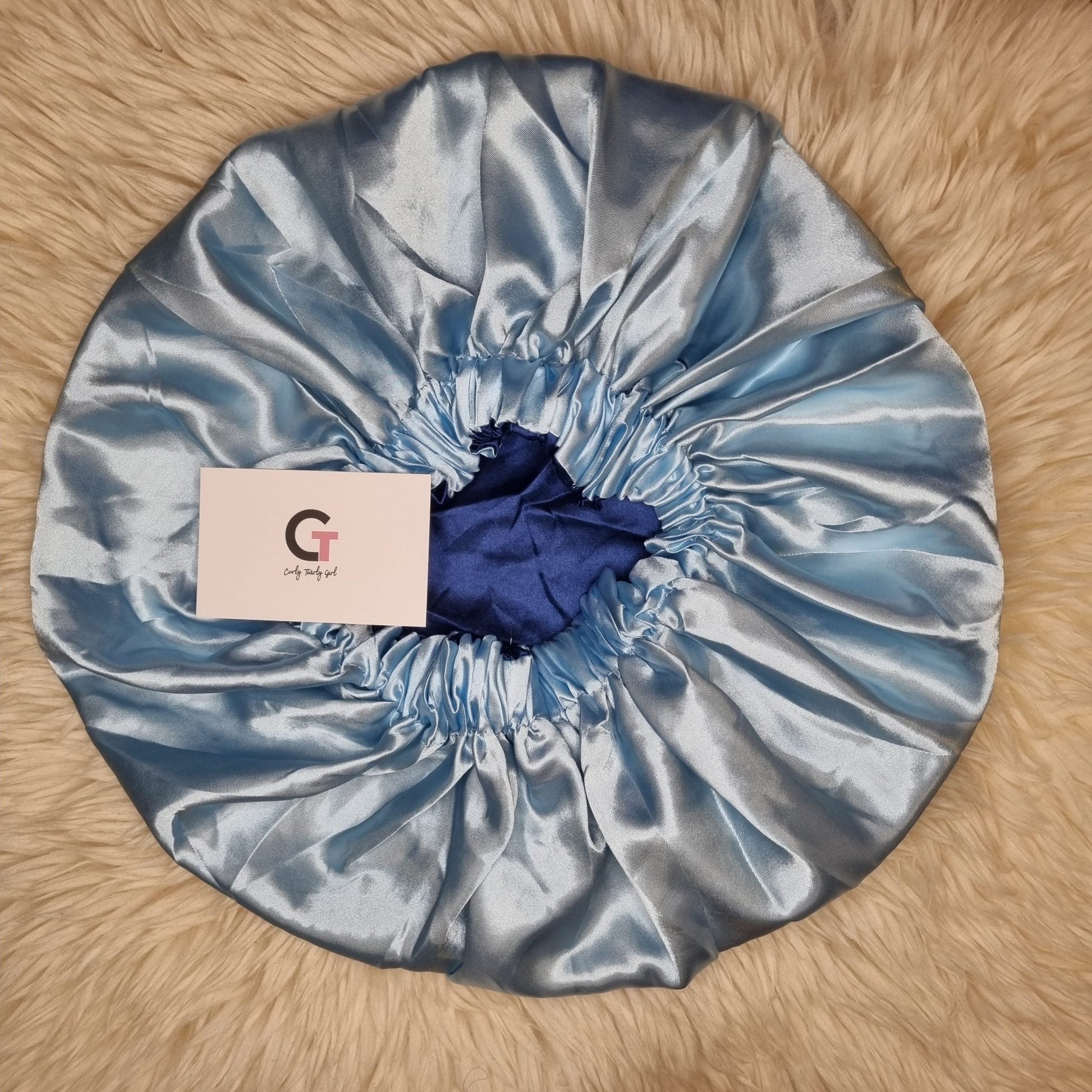 Ice blue reversible satin bonnet on cream rug
