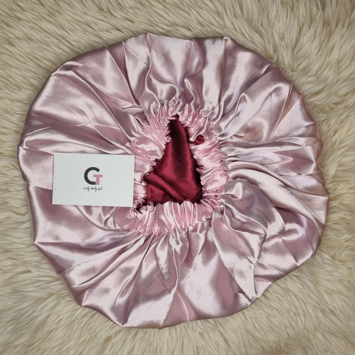 Pink reversible satin bonnet on cream rug