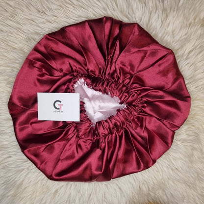Red reversible satin bonnet on cream rug
