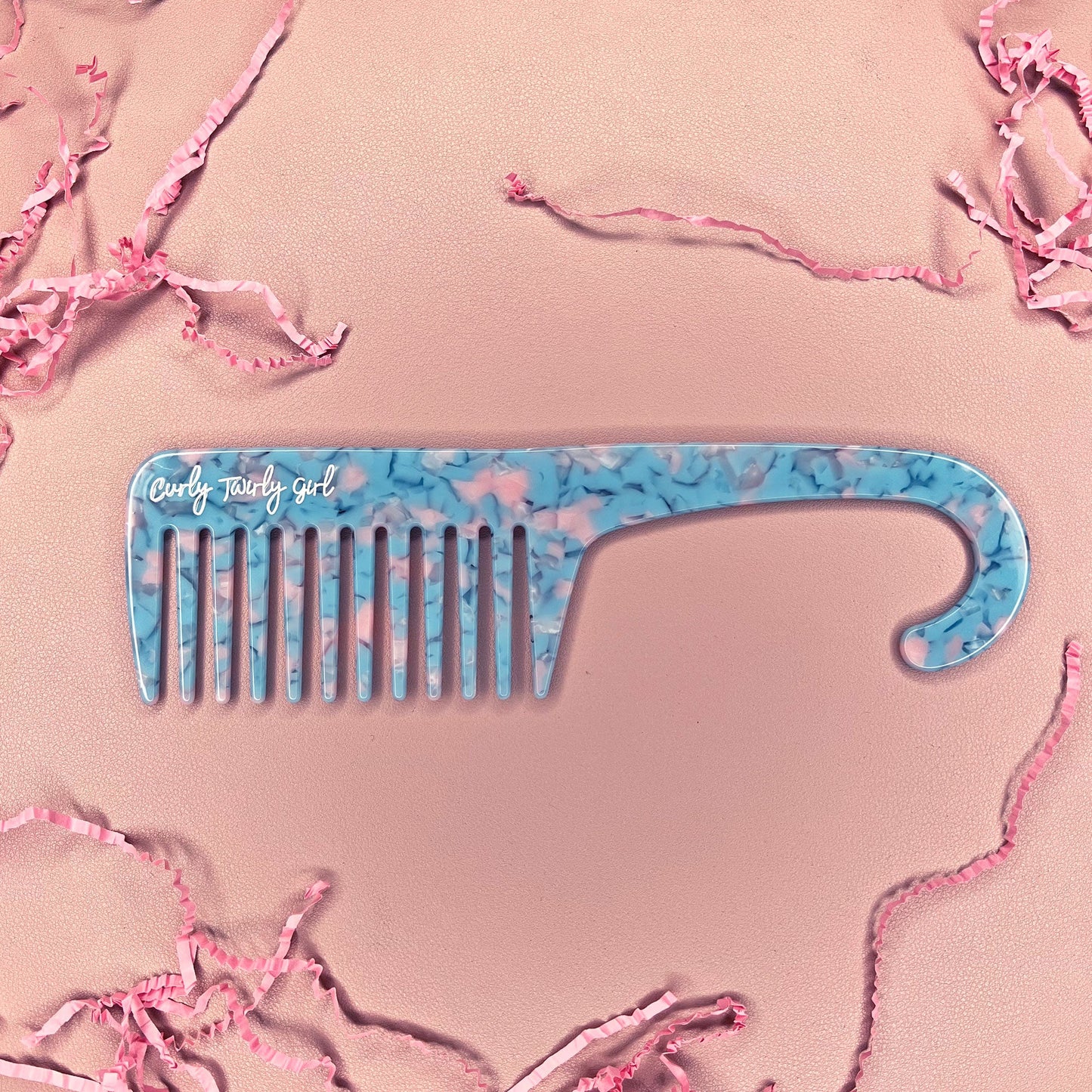 Blue wide tooth shower comb on pink table 