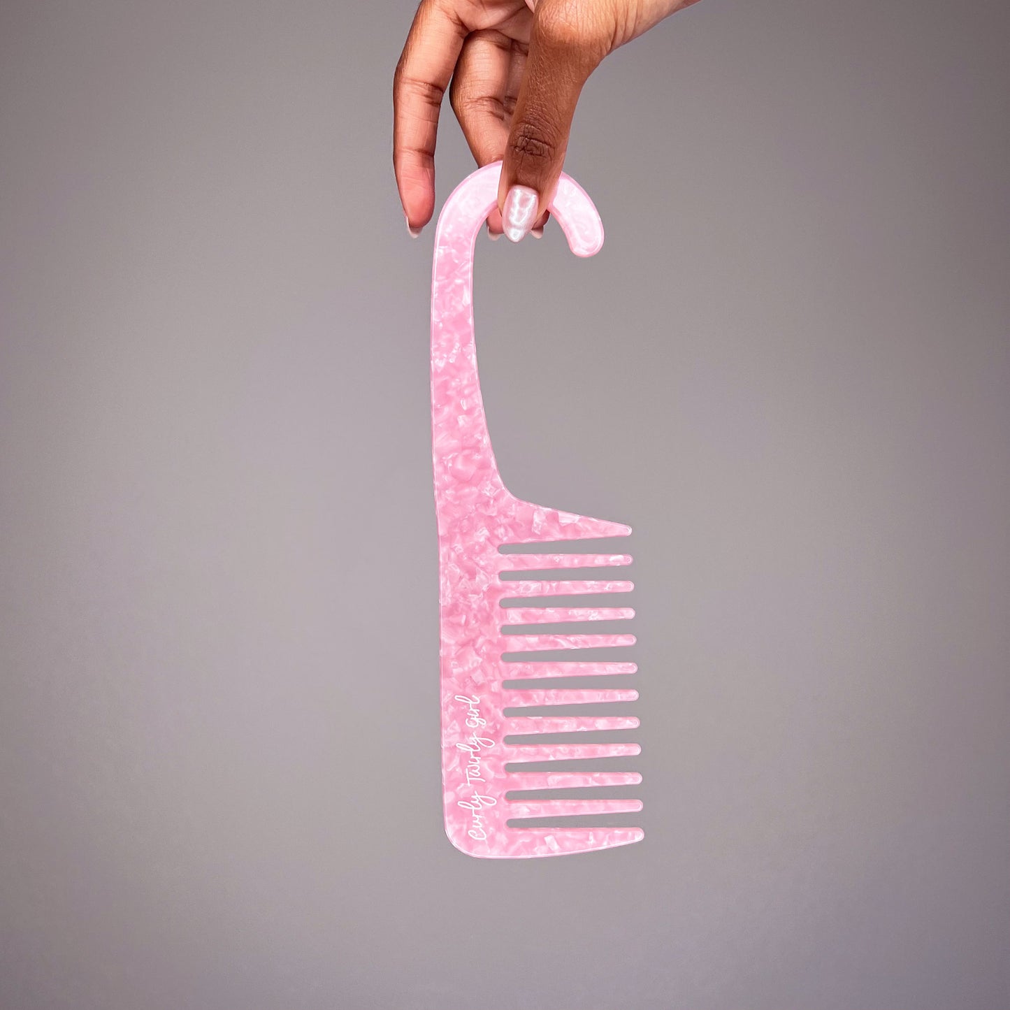 Hand holding pink wide tooth shower comb with hook