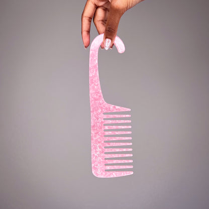 Hand holding pink wide tooth shower comb with hook