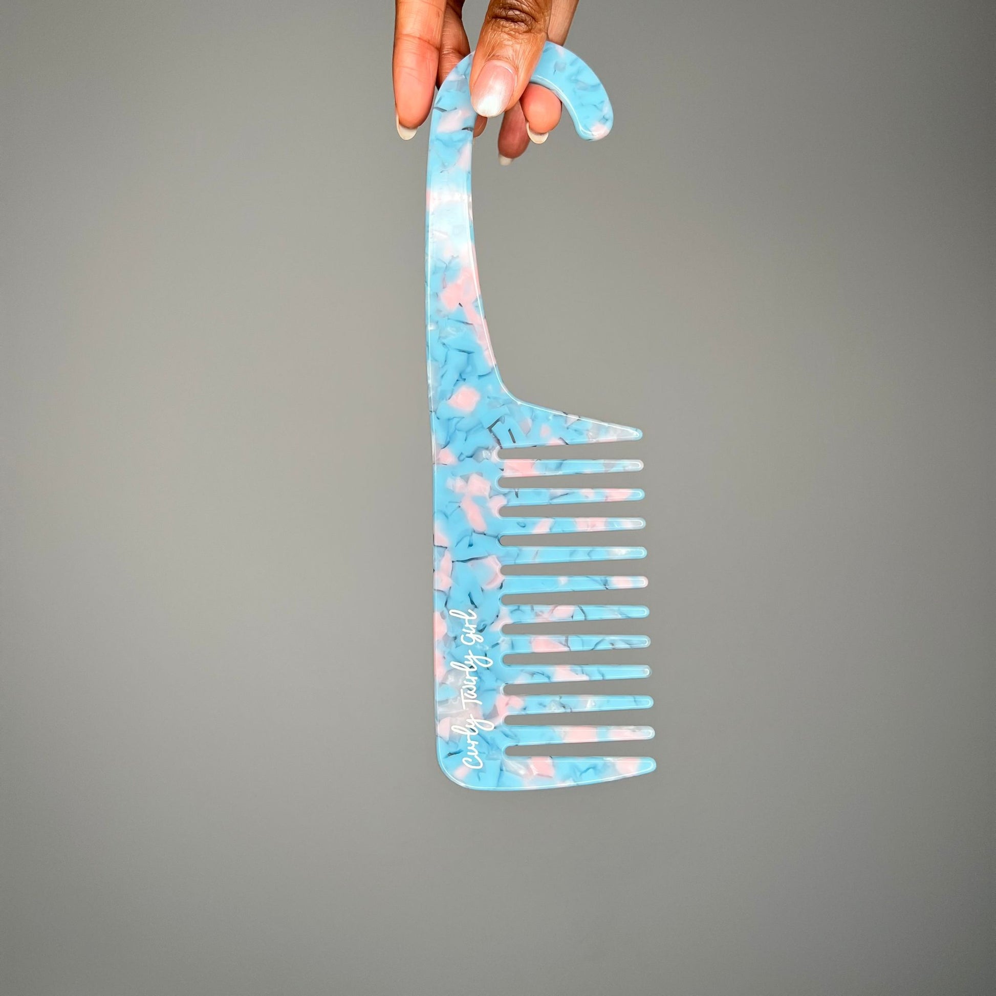 Hand holding a blue wide tooth shower comb