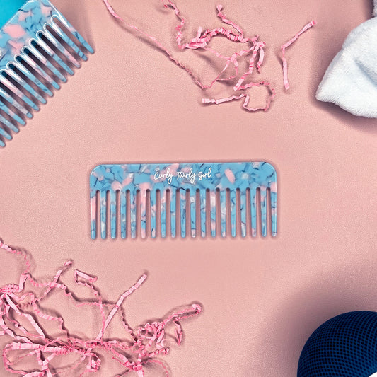 Blue wide tooth comb on pink table 